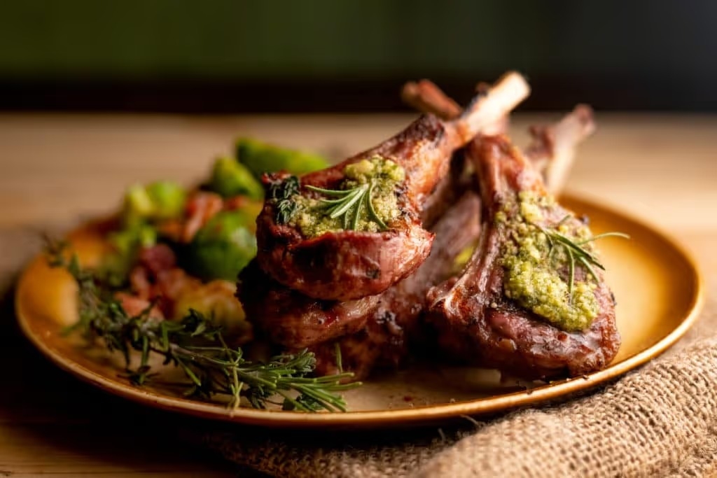 Charcoal grilled rack of lamb chops topped with pesto and rosemary