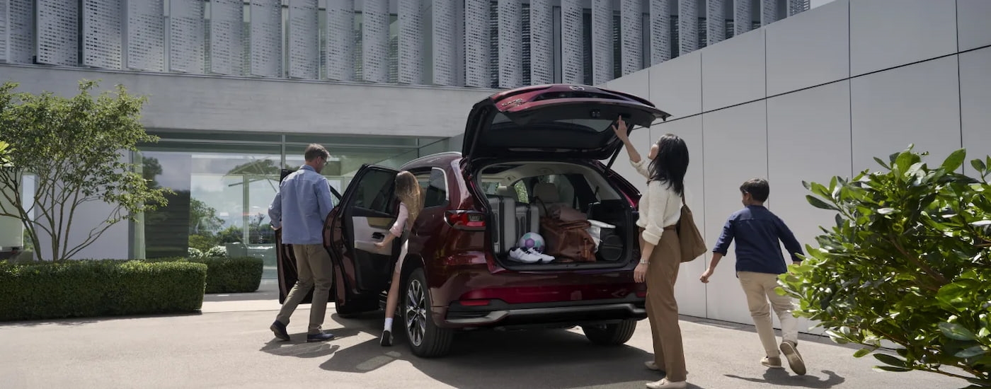 Family loading up the rear of a red 2026 Mazda CX-90.