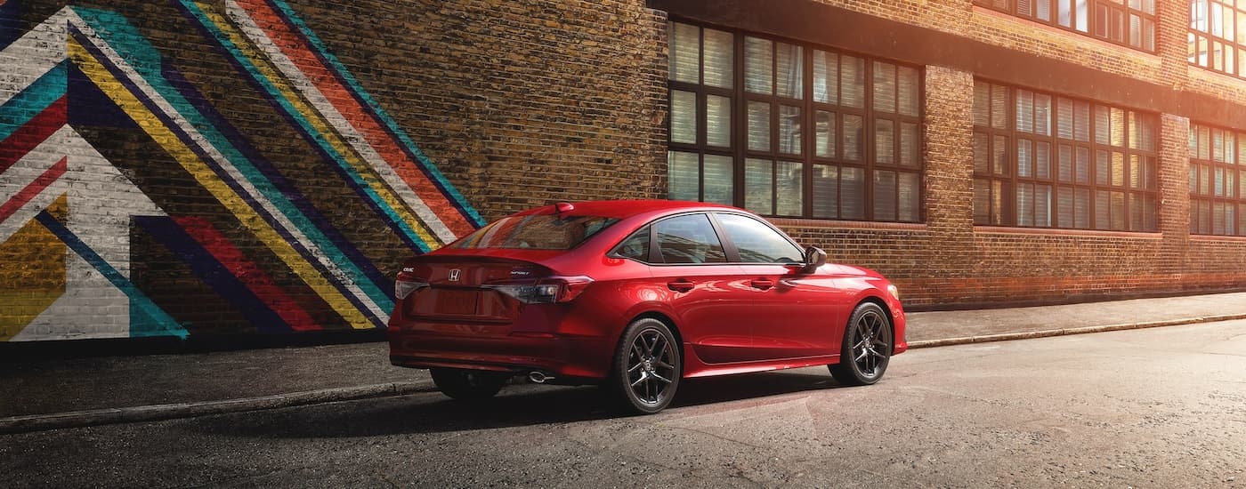 Rear of a red 2022 Honda Civic Sport parked by a brick wall.