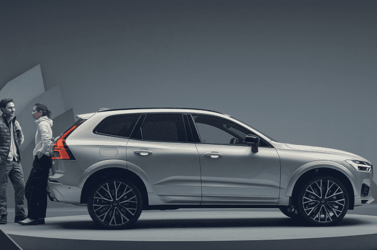 Two people standing next to a Volvo