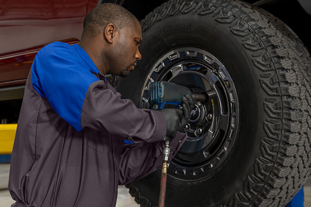 Ford service technician performing tire and wheel maintenance on a vehicle.