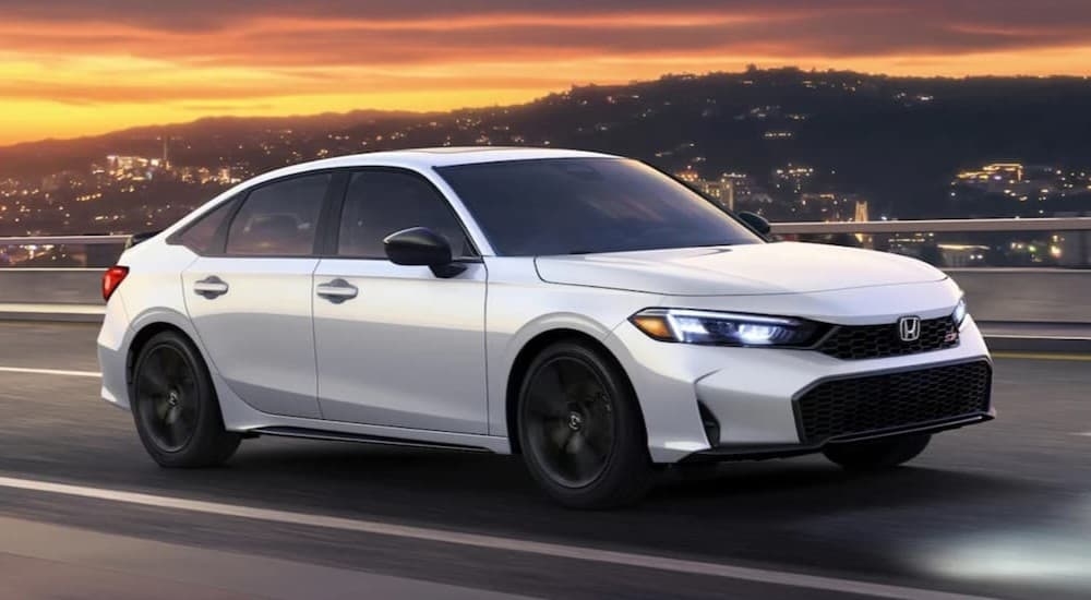 A white 2026 Honda Civic Si driving on a highway.