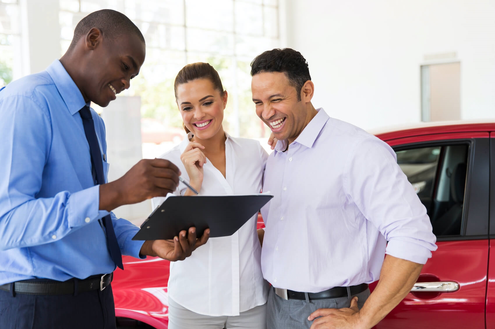 Sales man and customers in front of red car