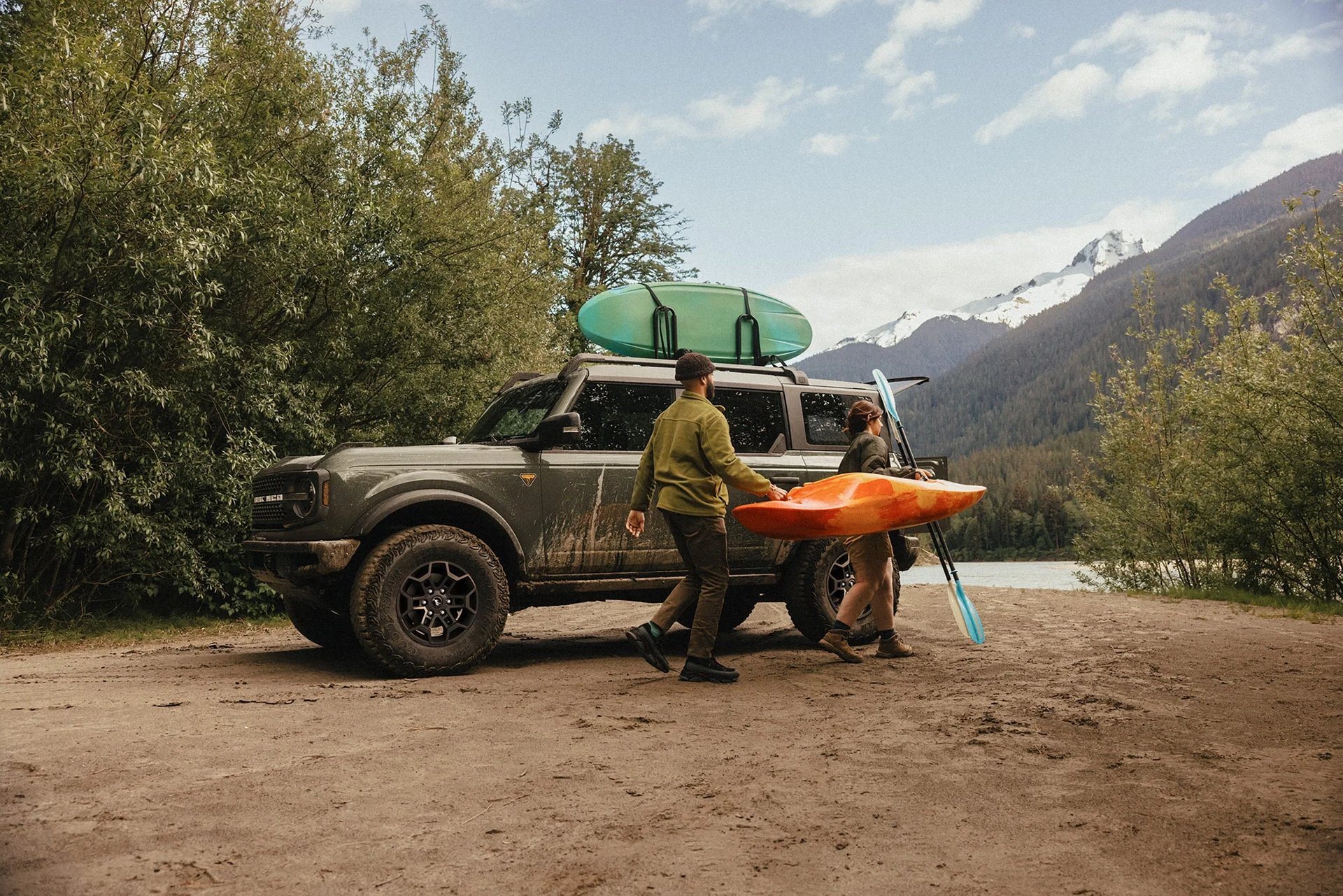 Couple carrying a kayak away from a 2026 Ford Bronco, using the cargo room a two-row layout leaves