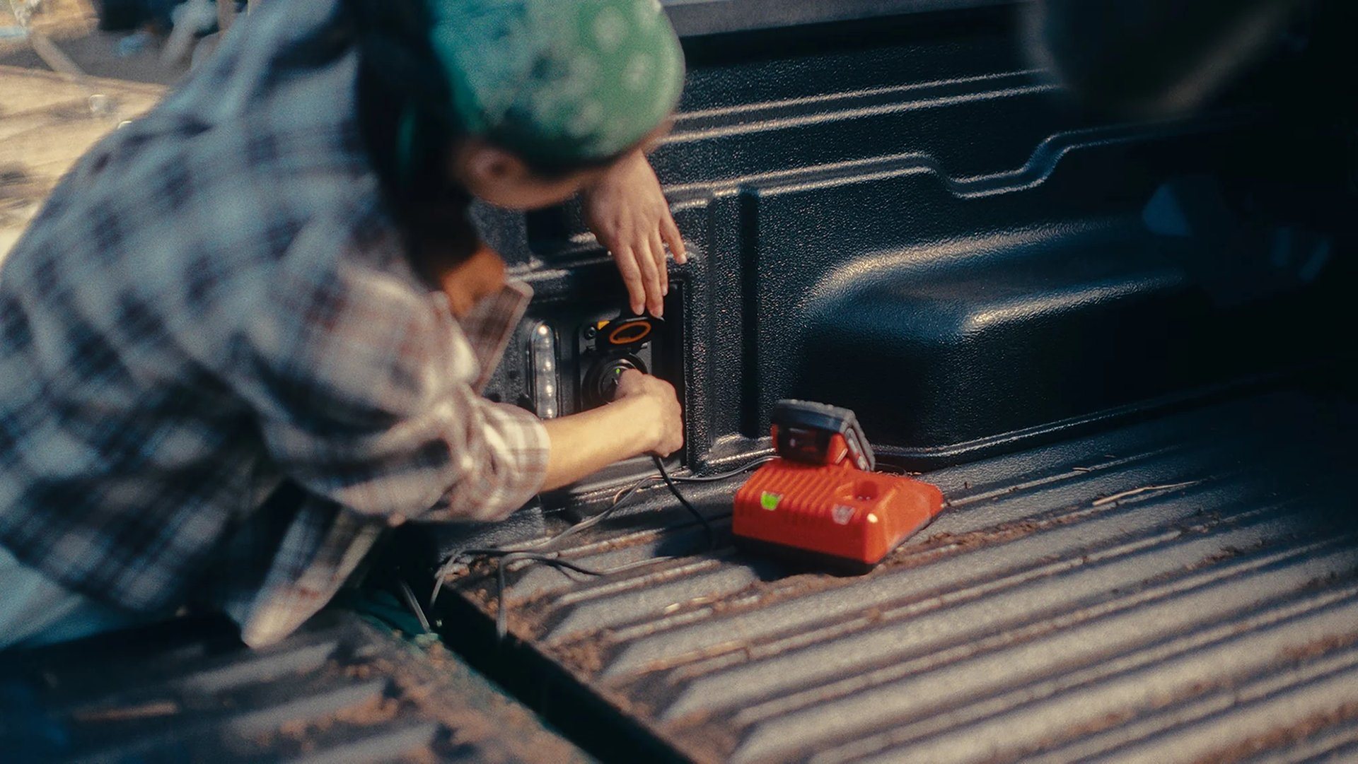 Person using the built-in power outlet in the bed of a 2026 Ford Maverick