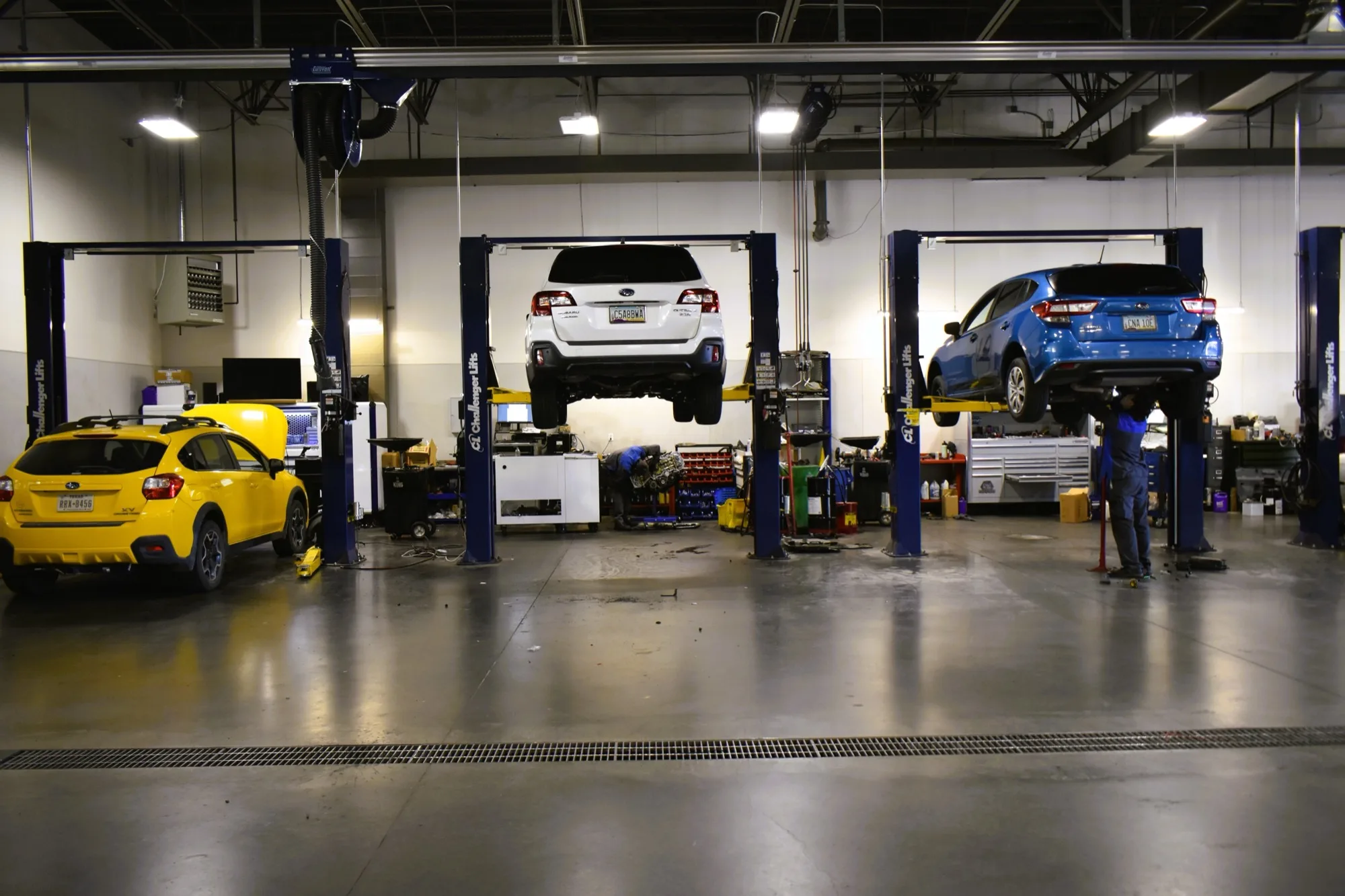 Subarus up on the lifts inside the Findlay Subaru Prescott service shop, a technician working underneath, with the tools and equipment for a proper AC diagnosis on hand.