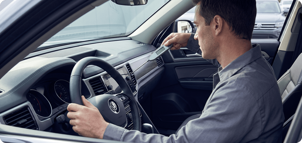 Technician measuring vent air temperature with a probe thermometer from the driver's seat of a Volkswagen