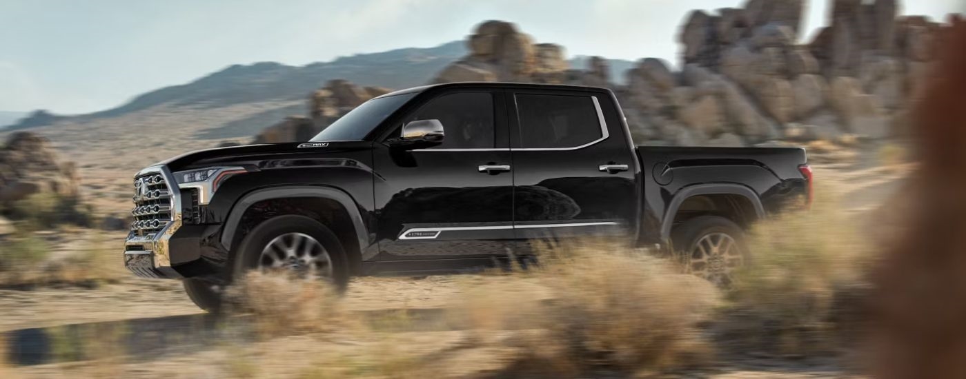 A black 2026 Toyota Tundra 1794 Edition Hybrid CrewMax driving off-road.