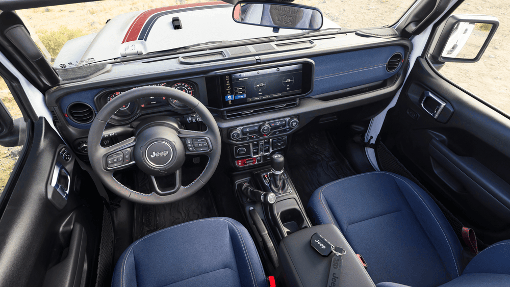 2026 Jeep Wrangler cockpit in Margate FL with navy blue dash, Jeep steering wheel, and touchscreen