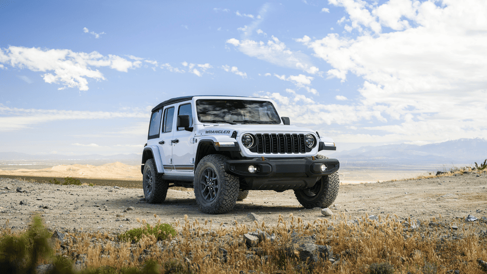 2026 Jeep Wrangler in Margate FL in white with round LED headlights and off-road tires on desert terrain