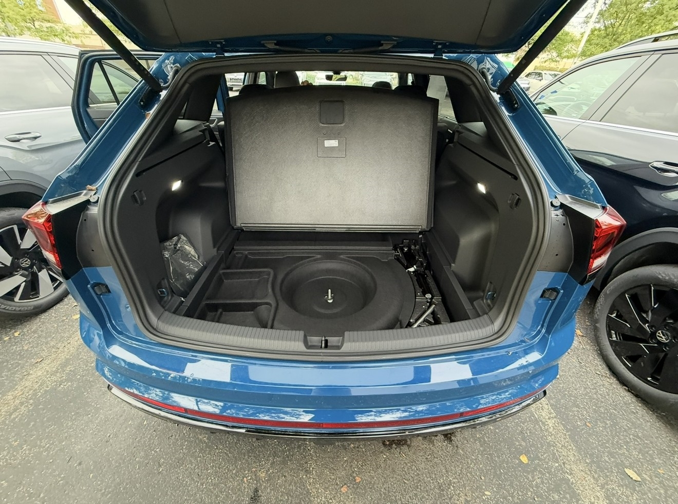 Cargo floor lifted in a Volkswagen SUV revealing the compact spare tire and tool kit underneath