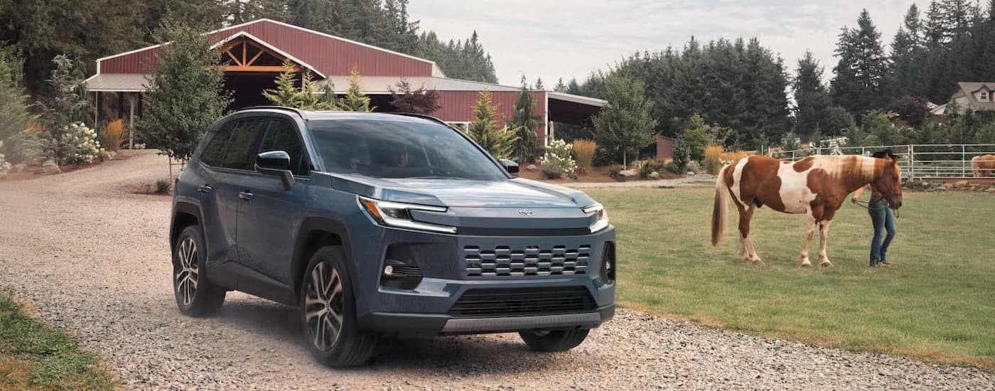 A blue 2026 Toyota RAV4 driving on a farm.