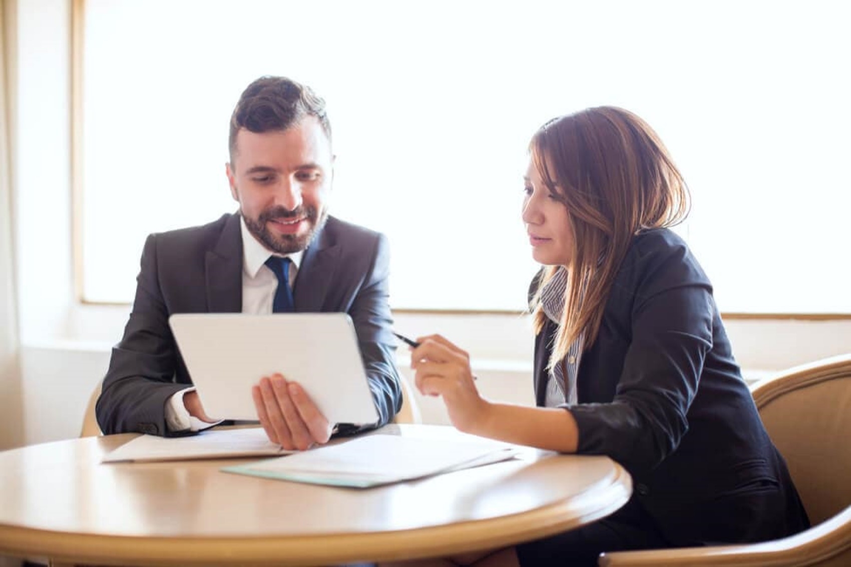 A man and woman discuss financing holding papers in an office.