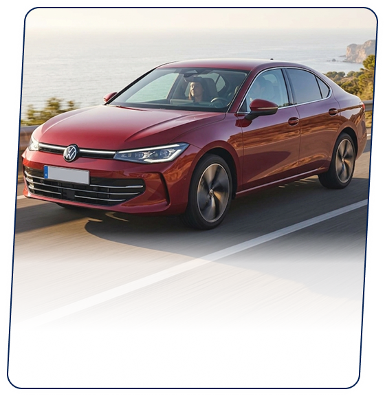 Red Volkswagen sedan driving along a coastal highway
