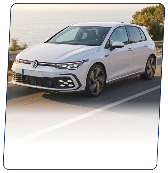 White Volkswagen hatchback driving along a coastal highway