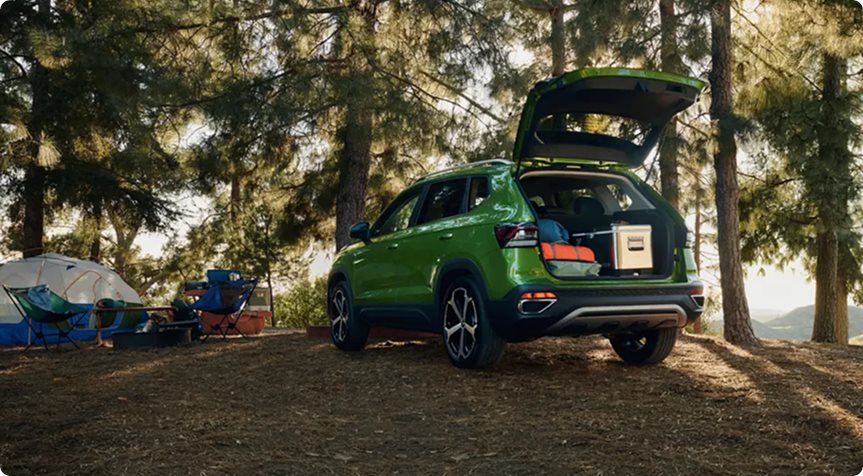 Green 2027 Volkswagen Taos with its tailgate open at a forest campsite