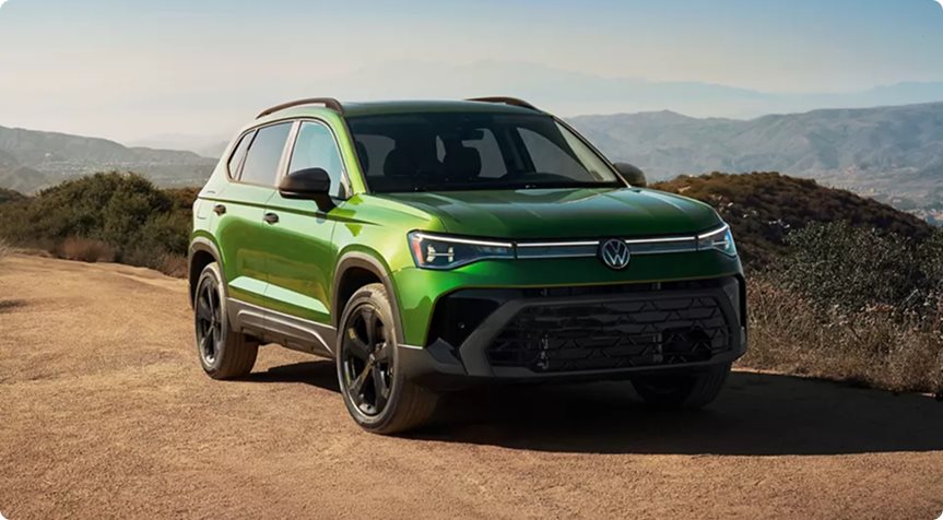 Green Volkswagen Taos SE Black with black wheels and exterior accents on a hilltop road