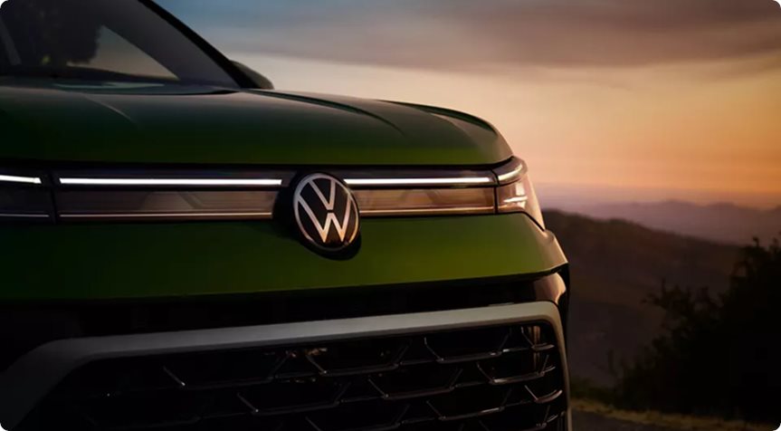 Illuminated grille light bar and VW logo on a green Volkswagen Taos at sunset