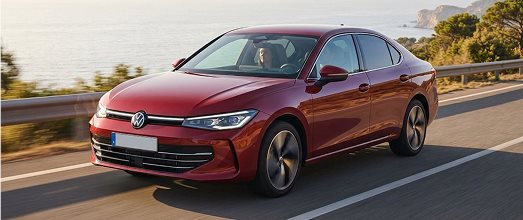 Red Volkswagen sedan driving along a coastal highway