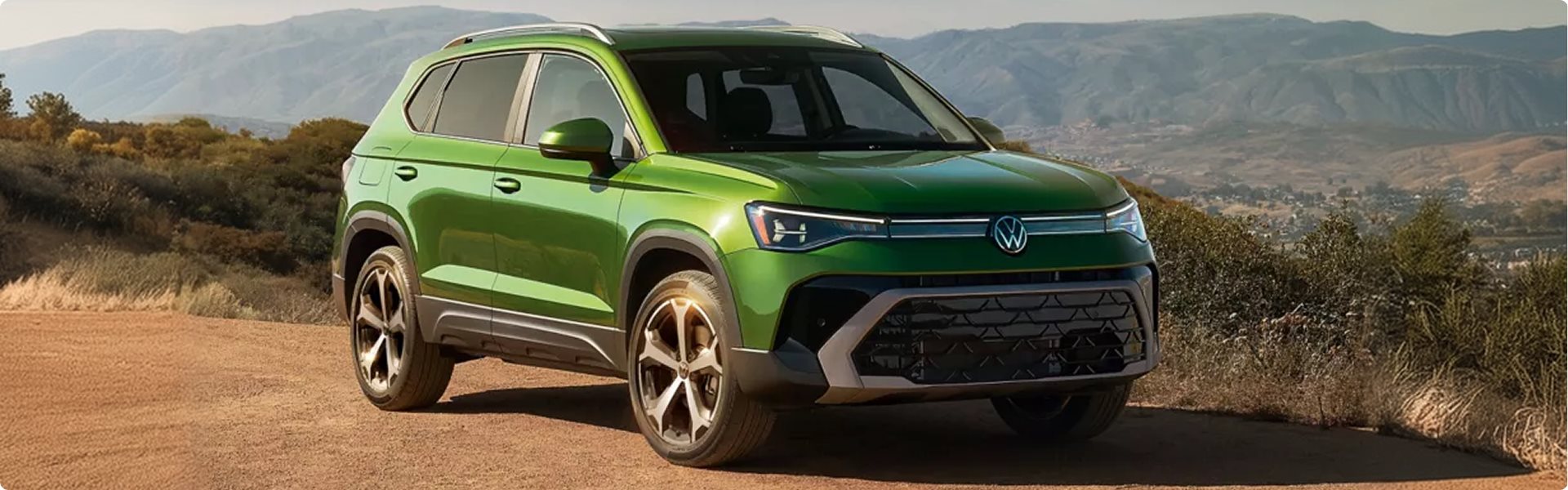 Green 2027 Volkswagen Taos parked on a dirt overlook in the hills