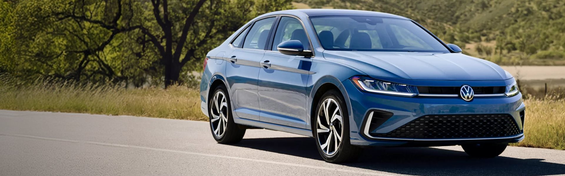 Blue 2027 Volkswagen Jetta driving along a country road