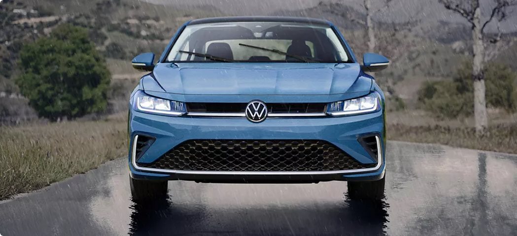 Blue 2027 Volkswagen Jetta on a wet road with its headlights on