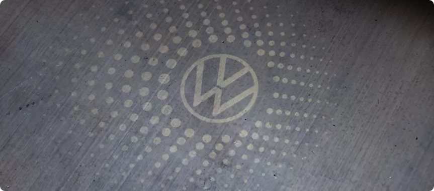 VW logo projected onto the pavement by a side-mirror puddle light