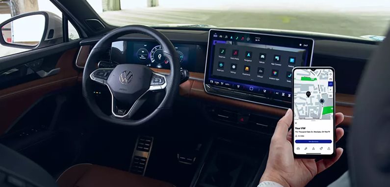 Passenger holding a smartphone with a map beside the Volkswagen Tiguan touchscreen