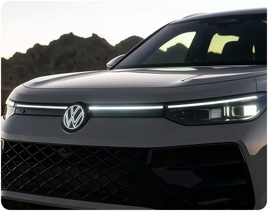 Front of a gray Volkswagen Tiguan with its light bar and illuminated VW emblem