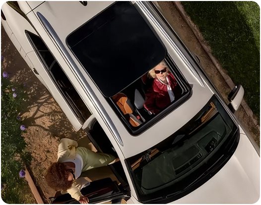 Overhead view of a white Volkswagen Tiguan with passengers looking out of the open sunroof