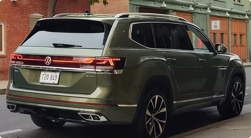Rear view of a green Volkswagen Atlas parked on a brick-lined street
