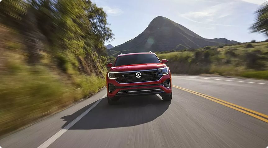 Red Volkswagen Atlas R-Line driving toward a mountain