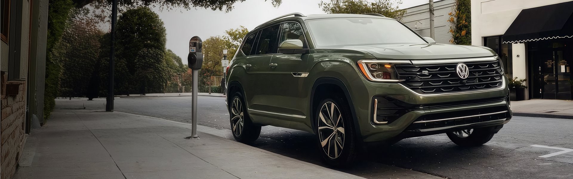 Green 2026 Volkswagen Atlas parked on a tree-lined city street