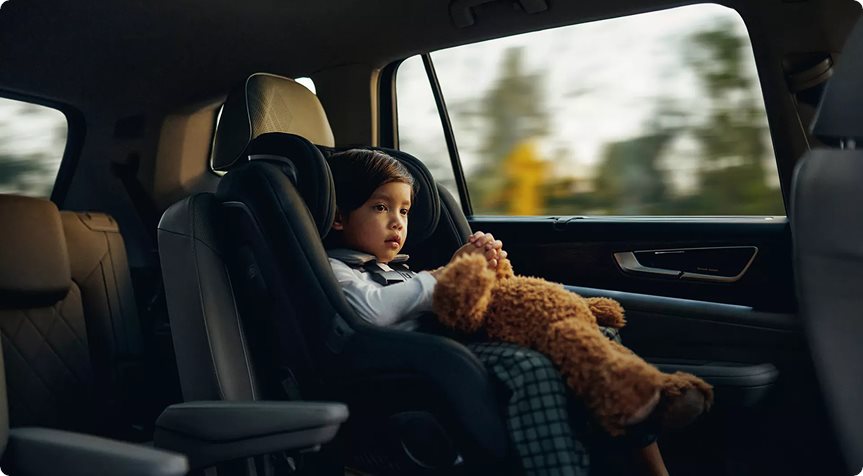 Child in a car seat looking out the rear window of the Volkswagen Atlas