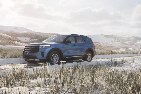Blue Ford Explorer driving through a snow-covered landscape with rolling hills in the background.