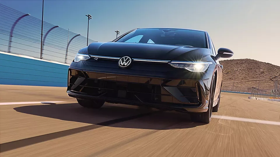 Black 2026 Volkswagen Golf R cornering on a racetrack under a clear sky