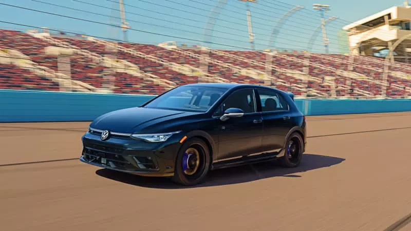 Black 2026 Volkswagen Golf R driving on a racetrack beside the grandstands