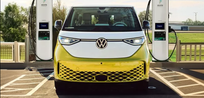 Yellow and white ID. Buzz charging between two Electrify America chargers