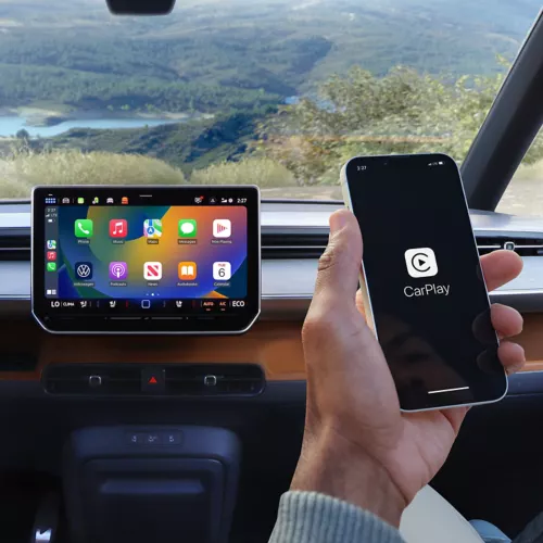 Hand holding a phone with Apple CarPlay beside the ID. Buzz touchscreen