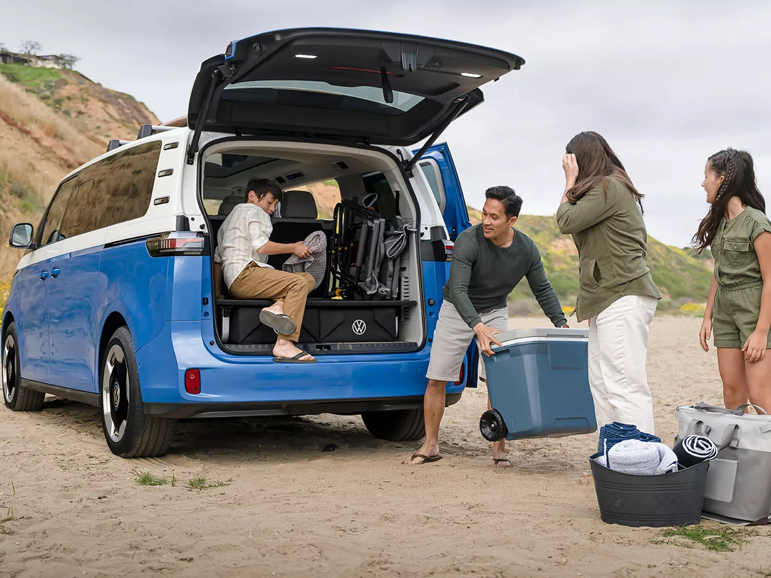 Family unloading camping gear from the open liftgate of an ID. Buzz on a beach