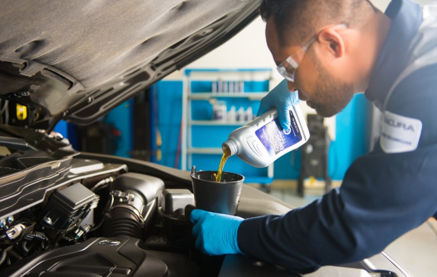 A close-up shot of an Acura Service Technician pouring oil into the engine of an Acura vehicle.
