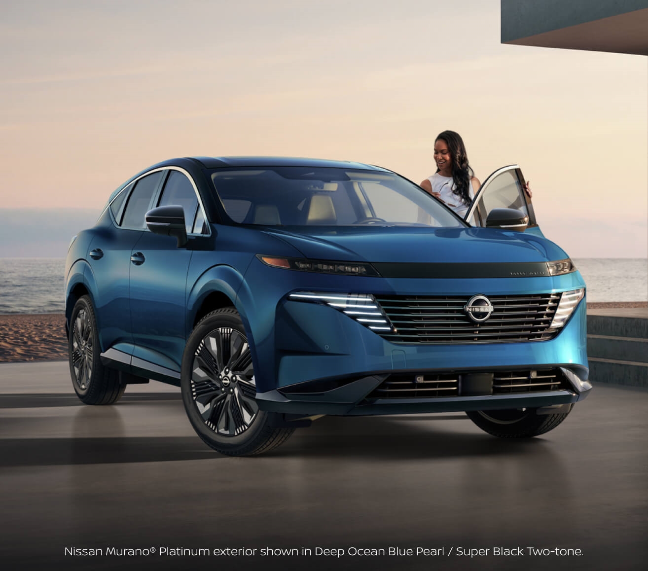 Front three-quarter view of a woman entering a 2027 Nissan Murano Platinum in Deep Ocean Blue Pearl and Super Black at sunset.