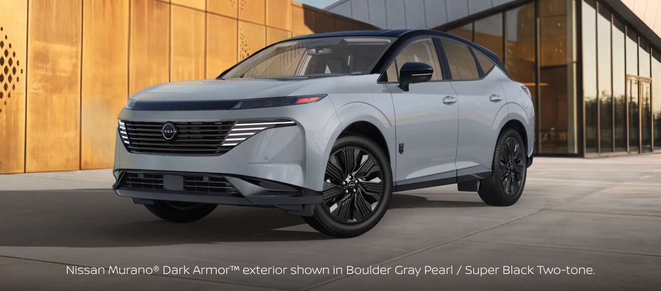 Front three-quarter view of a 2027 Nissan Murano Dark Armor in Boulder Gray Pearl and Super Black parked outside a modern building.