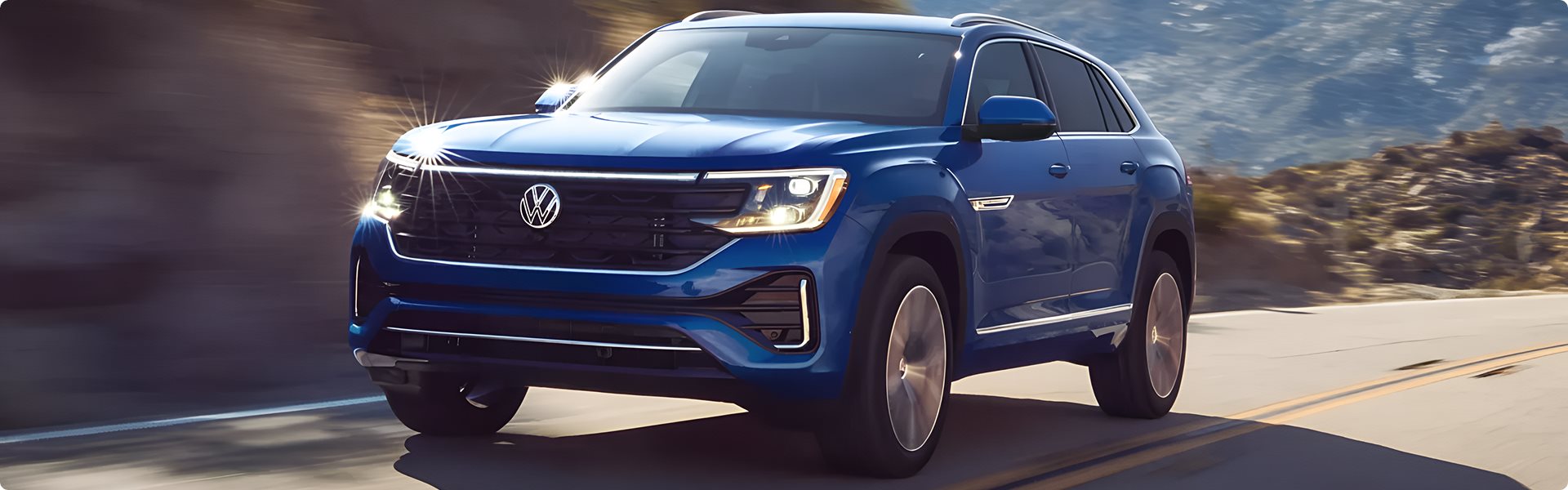Blue Volkswagen Atlas Cross Sport driving along a mountain road