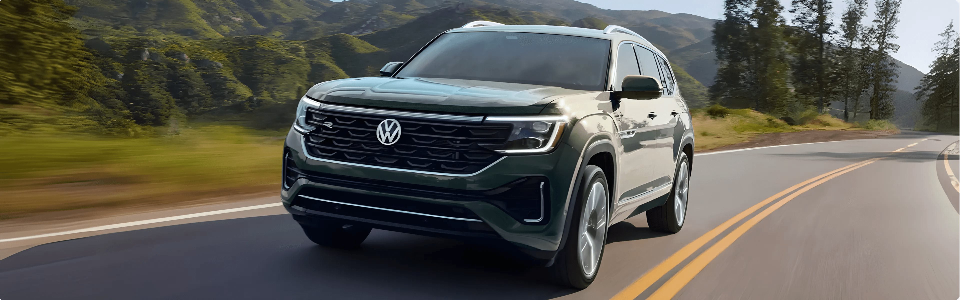 Green 2026 Volkswagen Atlas driving on a winding mountain road