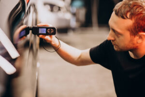 Technician inspecting a car's paint