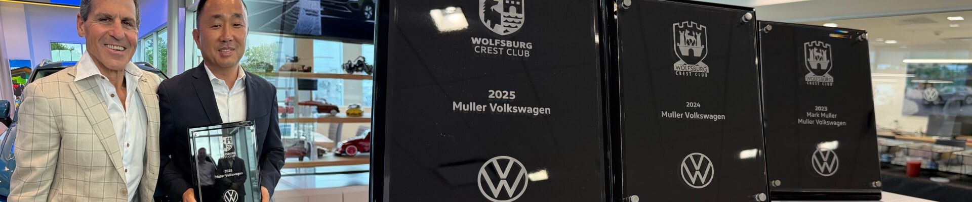 Two smiling men holding the 2025 Wolfsberg Crest Club award. A lineup of awards from 2025, 2024 and 2023.