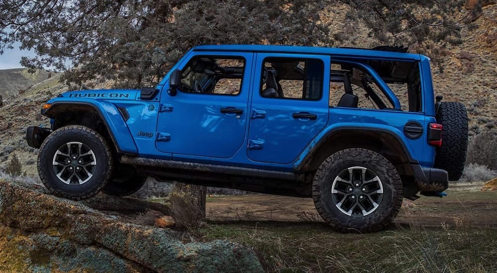 Side of a blue 2026 Jeep Wrangler parked off-road.