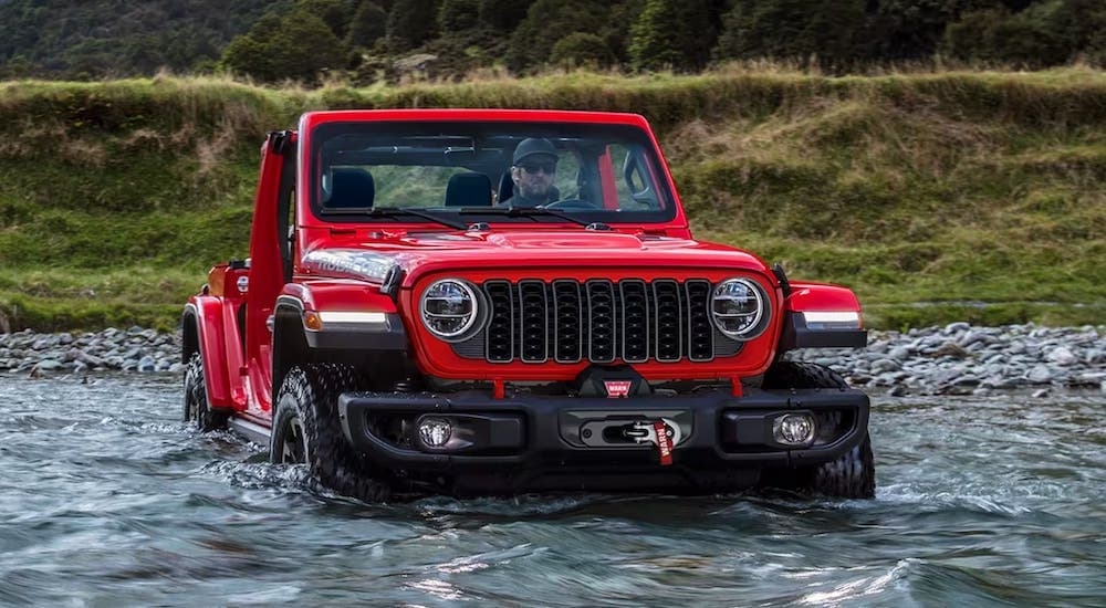 Red 2026 Jeep Wrangler driving through a shallow river.
