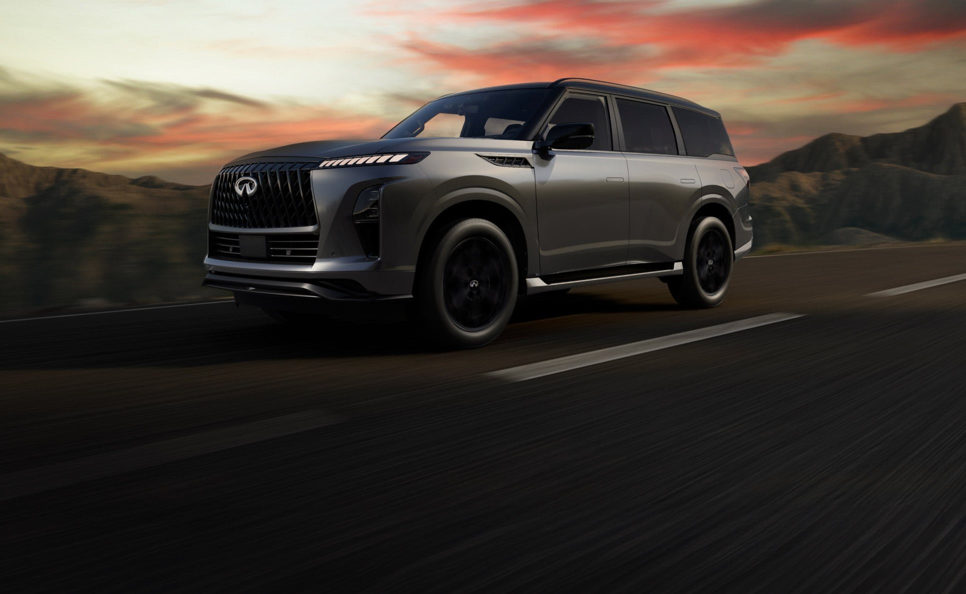 2027 INFINITI QX80 driving on a mountain highway at sunset